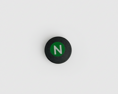 Round black magnet with a green 'N' on a white background