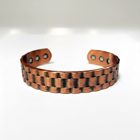A handmade copper cuff bracelet with a textured, hammered finish and darkened accents, displayed on a clean white background.