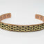 A copper-toned cuff bracelet with a textured gold-tone chain-link pattern on the front, photographed on a clean white background.