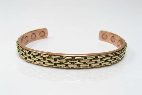 A copper-toned cuff bracelet with a textured gold-tone chain-link pattern on the front, photographed on a clean white background.