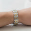 Hand wearing a silver and gold bracelet on a light background