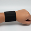 Black wrist support brace on a person's wrist against a light gray background