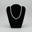 A classic pearl necklace displayed on a black velvet jewelry bust against a neutral gray background.