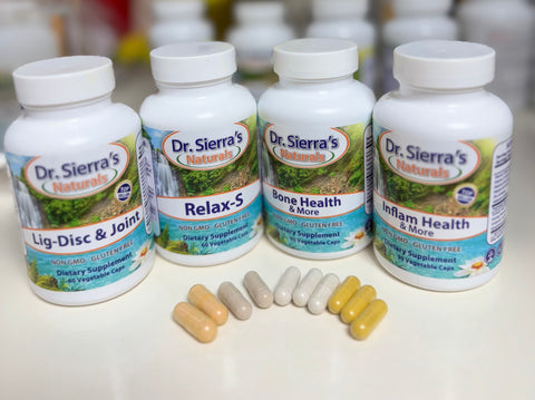 Four white bottles of Dr. Sierra's Naturals dietary supplements arranged in a row on a light surface, with five capsules placed in front.