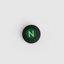 Round black magnet with a green 'N' on a white background