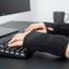Close-up of hands wearing wrist supports with thumb loops while typing